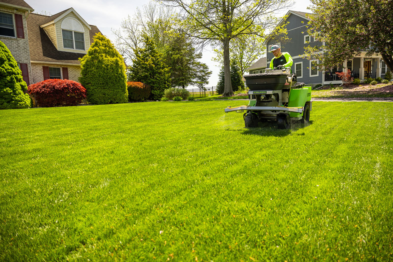 lawn care technician operating a lawn sprayer for weed control in front of a nice house 6