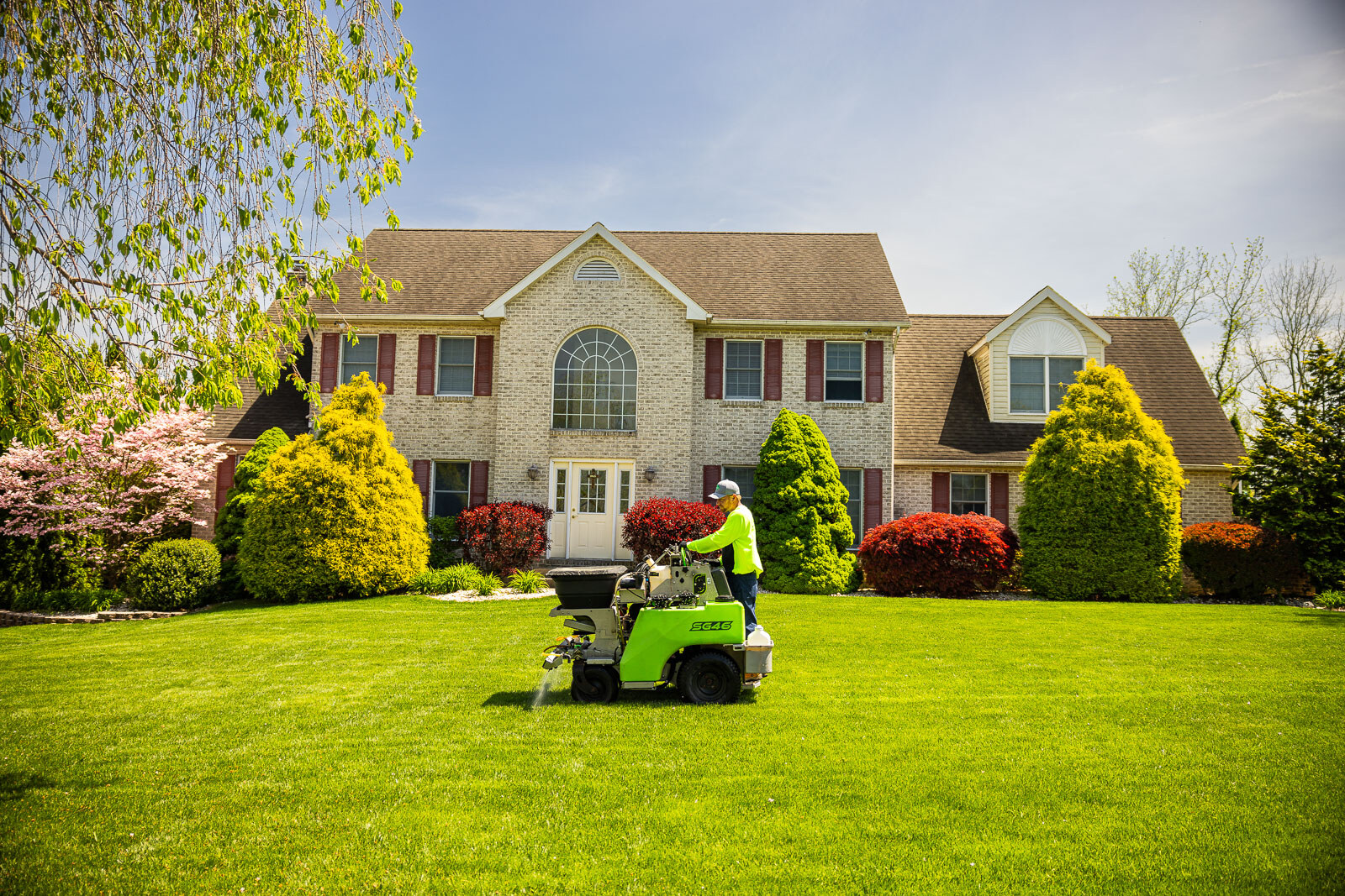 lawn care technician operating lawn spreader in backyard