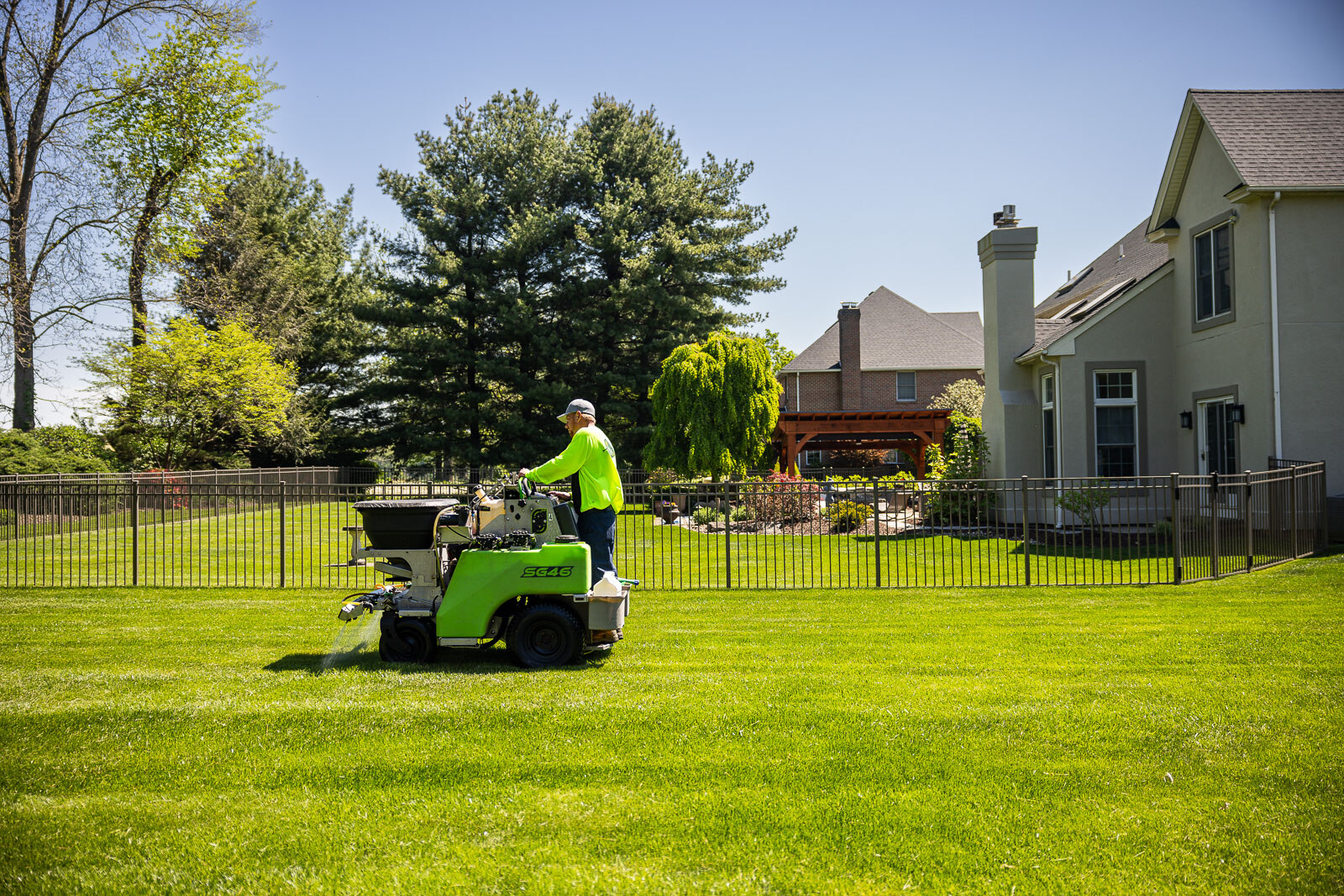 lawn care technician operating spreader in backyard 2