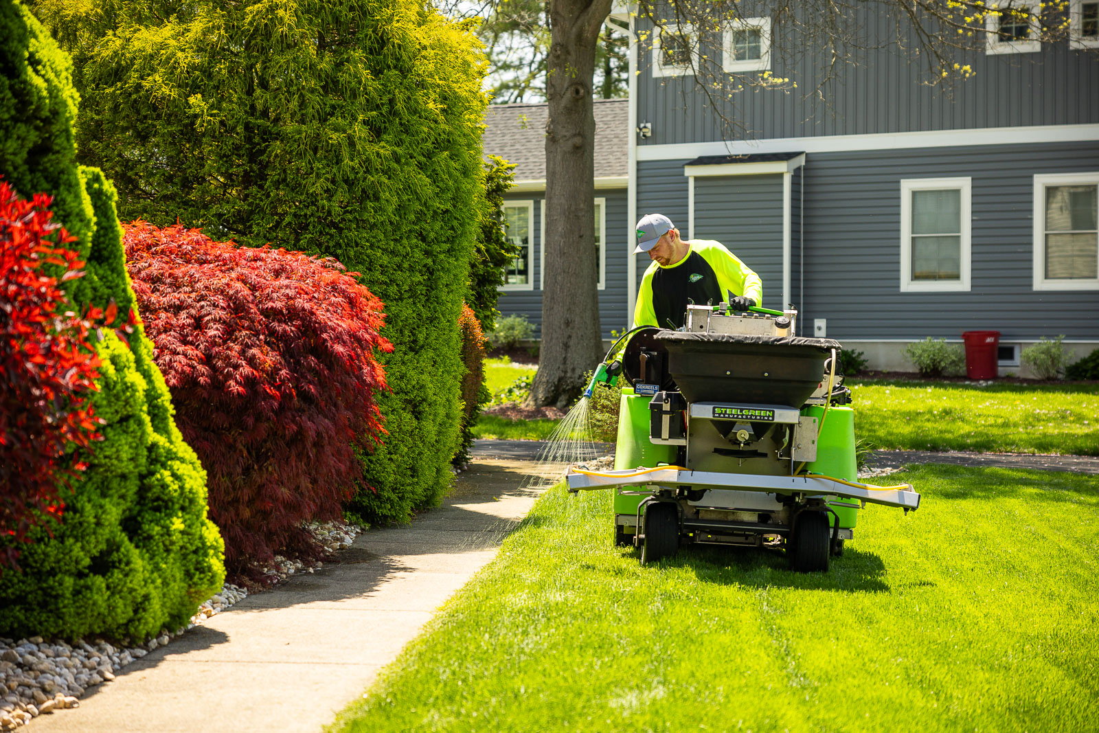 lawn care technician spraying yard edge with selective weed spray