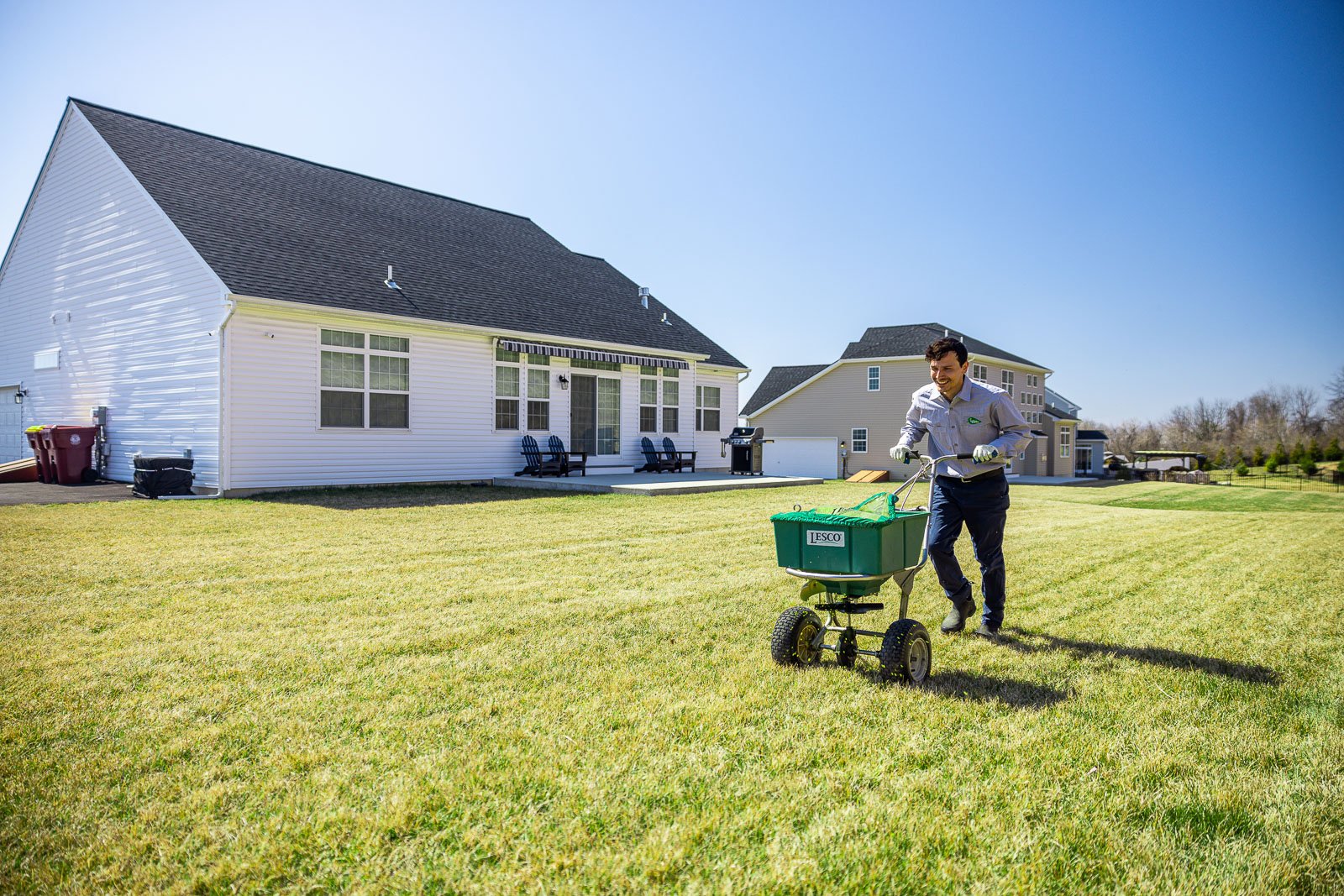 lawn care technician applying granular fertilizer to a dormant lawn